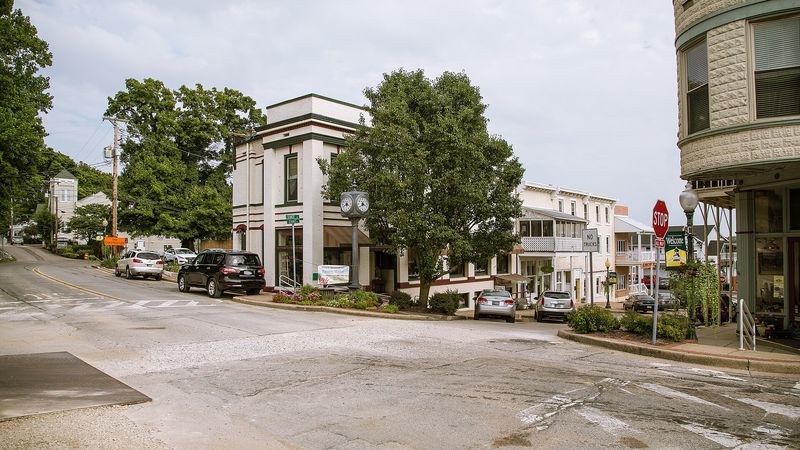 A downtown Newburgh street corner with two- and three-story historic buildings, a street clock and shade trees